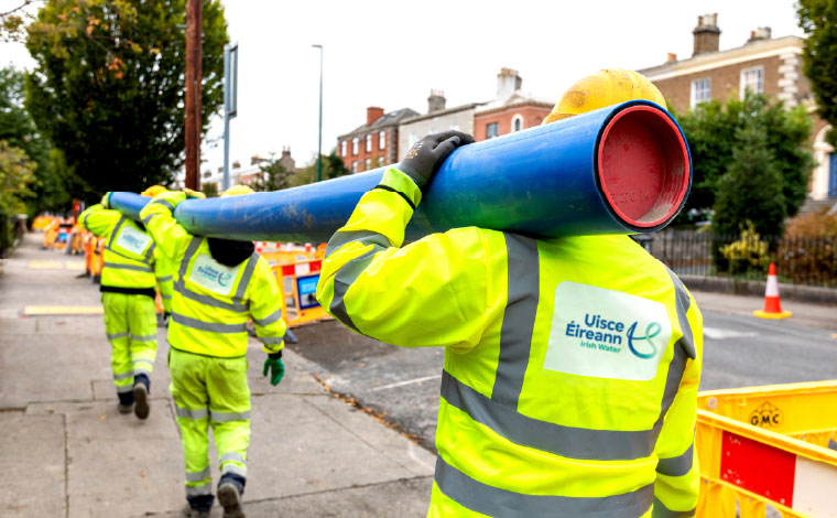 Leakage reduction programme workers carrying a pipe along a roadside