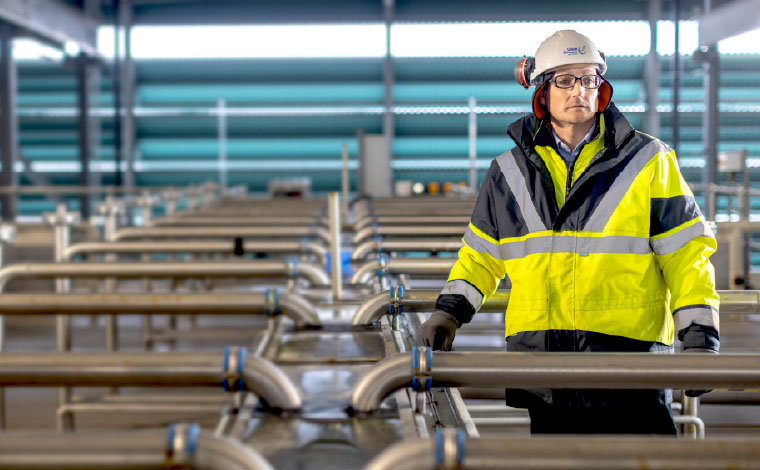 Wastewater Treatment plant manager standing inside the treatment plant among pipes