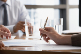 A hand holding a pen over papers on a table