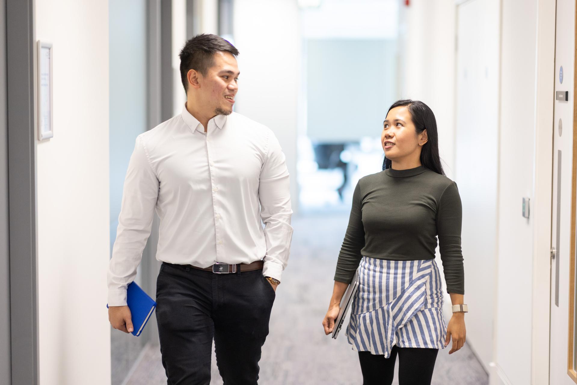 Two UÉ employees walking through the office halls