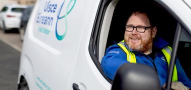 Uisce Éireann employee driving a white UÉ van
