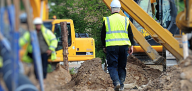A worker walking through the construction site surrounded by diggers and muck