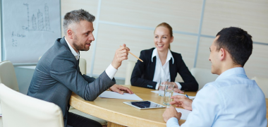 Three offices workers in the middle of a discussion in a meeting room