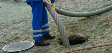 A man using a long hose / pipe to unblock a drain