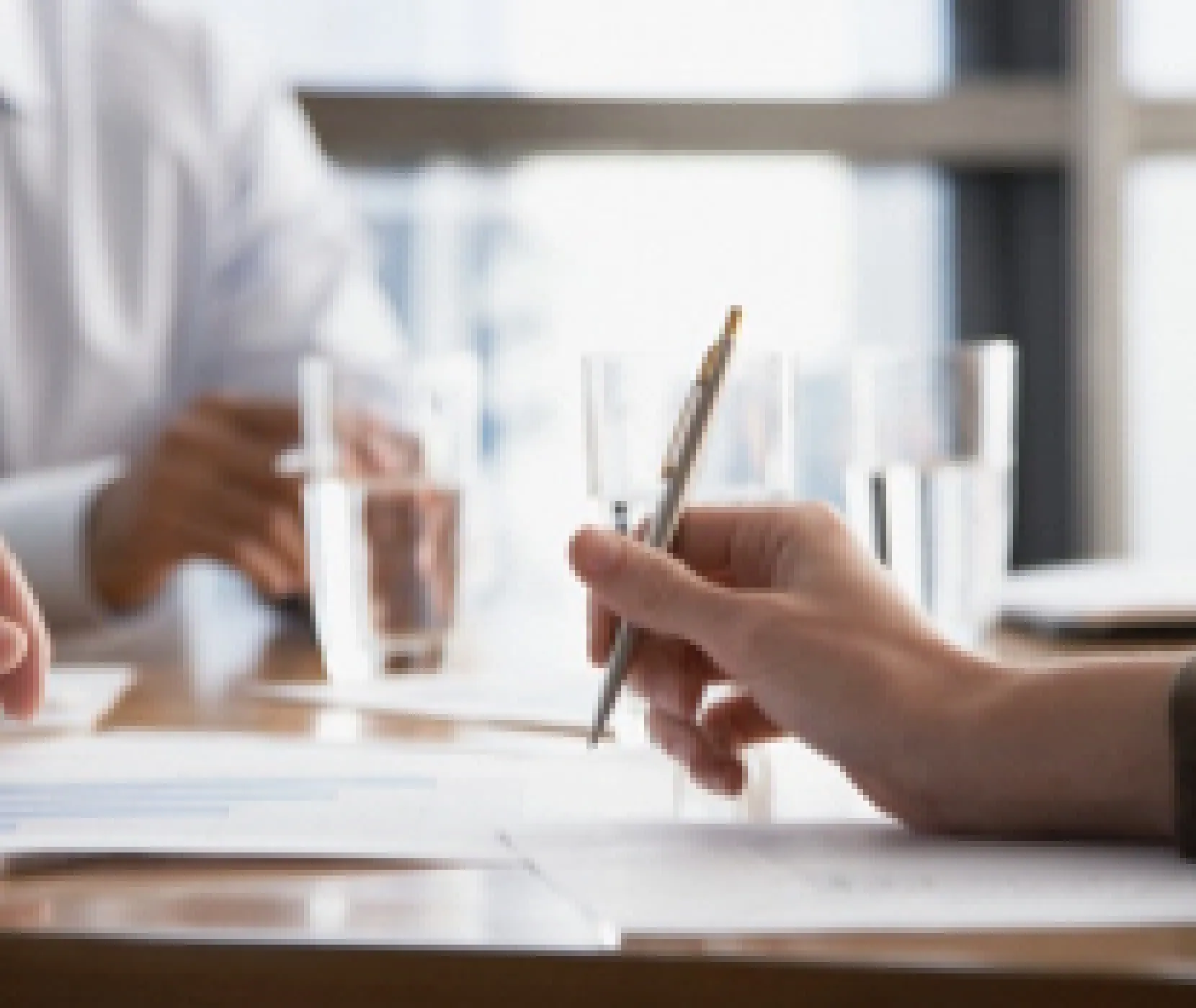 A hand holding a pen over papers on a table