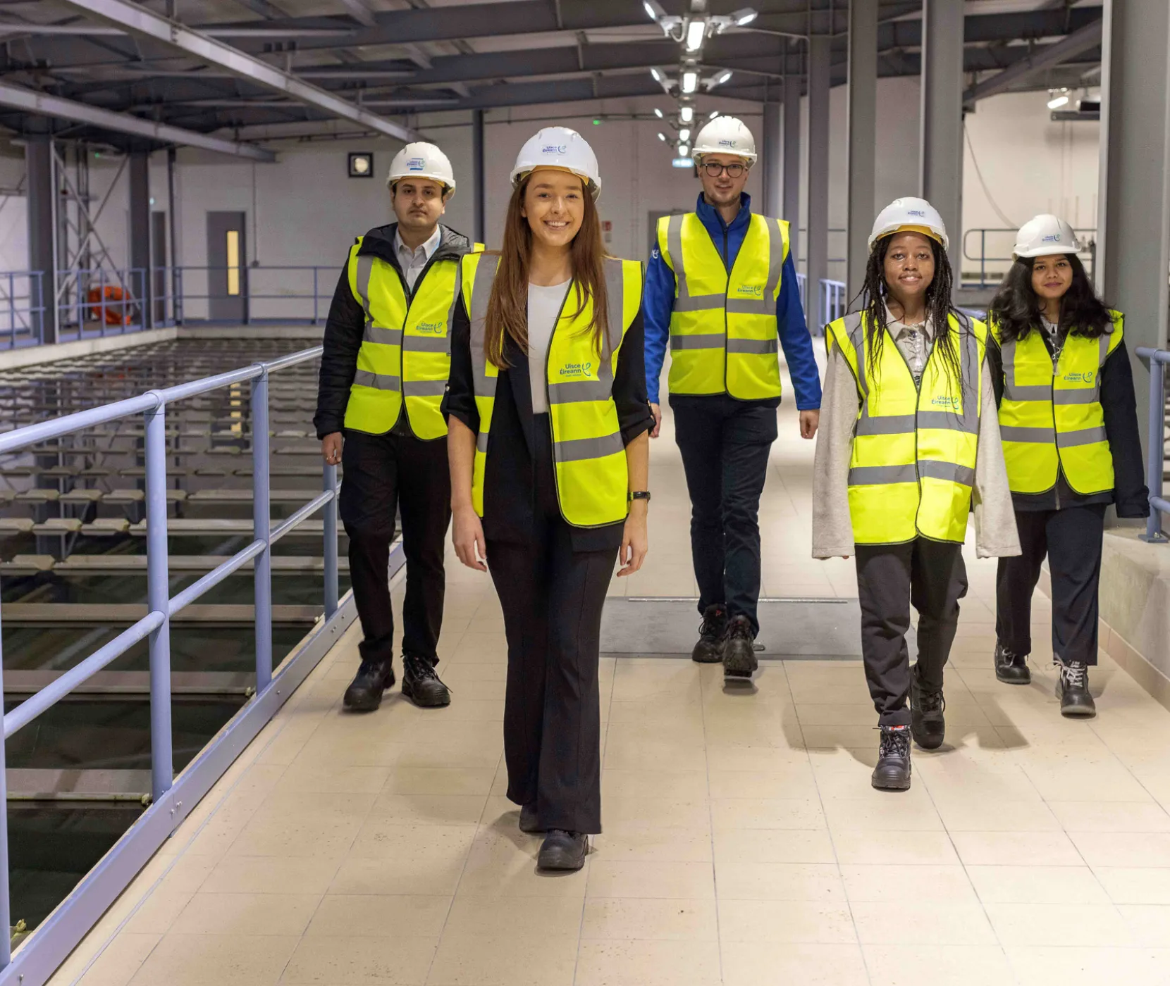 Five graduates walking in a water treatment plant