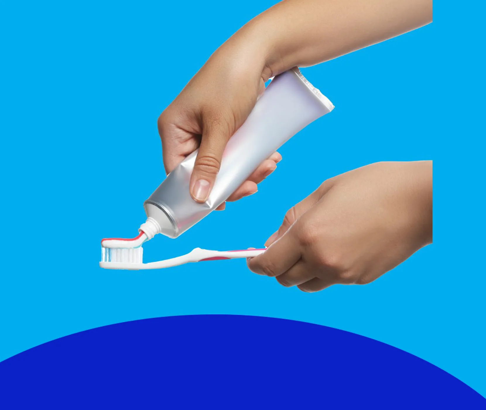 A person squeezing toothpaste on a toothbrush