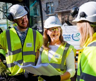 Three Uisce Éireann engineers holding site plans while smiling at eachother