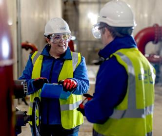 Two Uisce Éireann engineers beside a large pipe with water valves