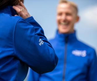 Two people with a blue Uisce Éireann full zip outfit and one person smiling at the other person