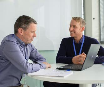 Two people having a meeting and one person is looking at the laptop