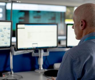 A UÉ office worker looking at multiple computer screens