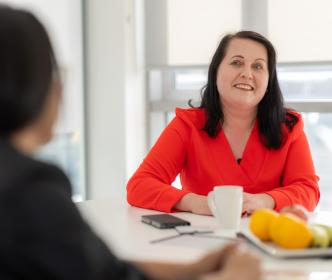 A UÉ office worker sitting with colleagues at a lunch table