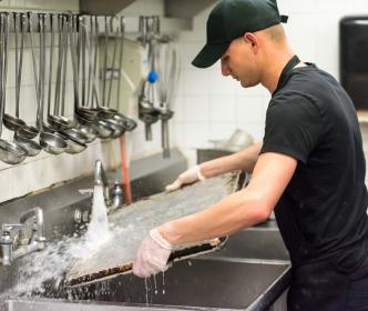 A kitchen worker washing baking trays in the restaurant kitchen