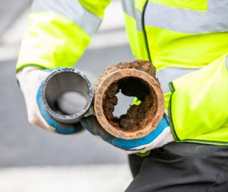 Two water pipes - one rusted and covered in grime build up while the other is brand new. 