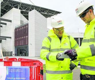 Two Uisce Éireann workers at a site by a big building